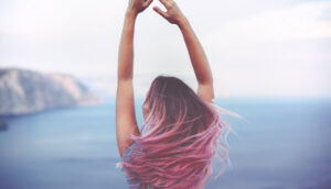 Girl with pink hair and arms in the air